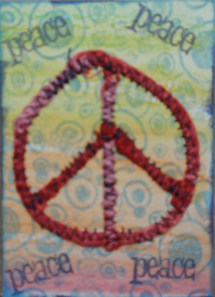 wc pencil background, stamped ink over, stamped Peace, took woven ribbon &amp; formed peace sign, zigzag stitch over